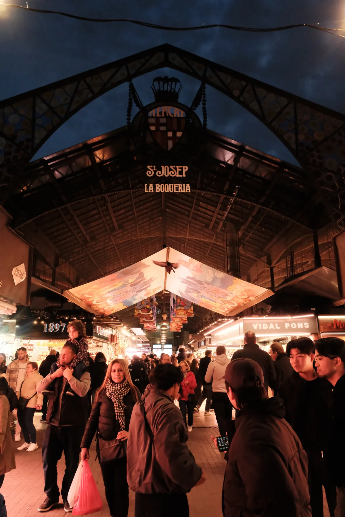 The busy central aisle and iron entrance of La Boqueria market in Barcelona