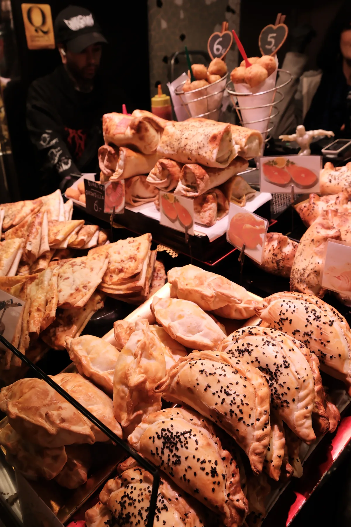 A market counter piled with golden savory pastries and filled breads