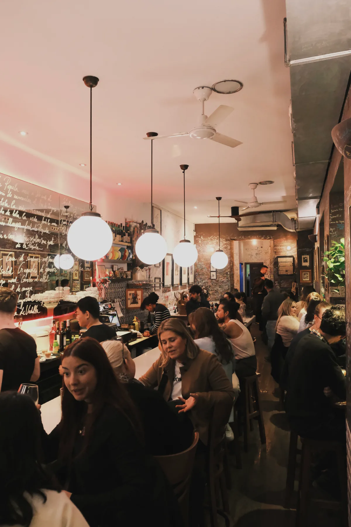 La Pepita's long narrow dining room filled with guests seated along the bar and small tables