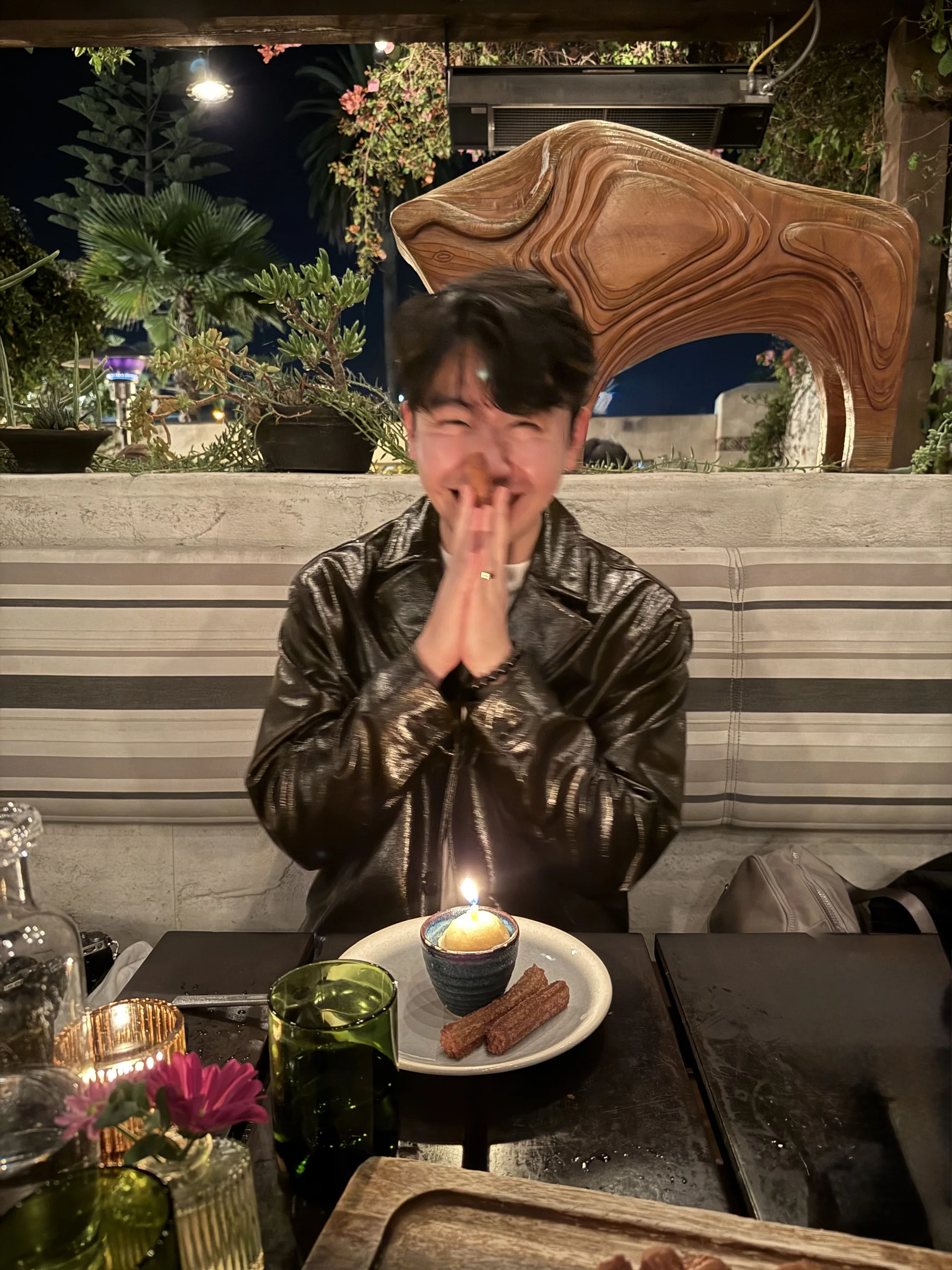 Shawn smiling behind a small birthday dessert with a lit candle