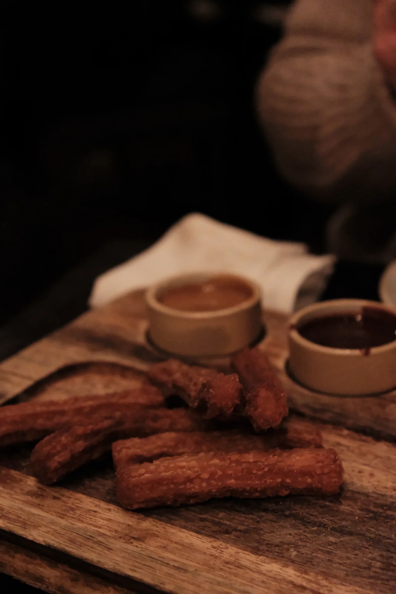 Churros served on a wooden board with two dipping sauces