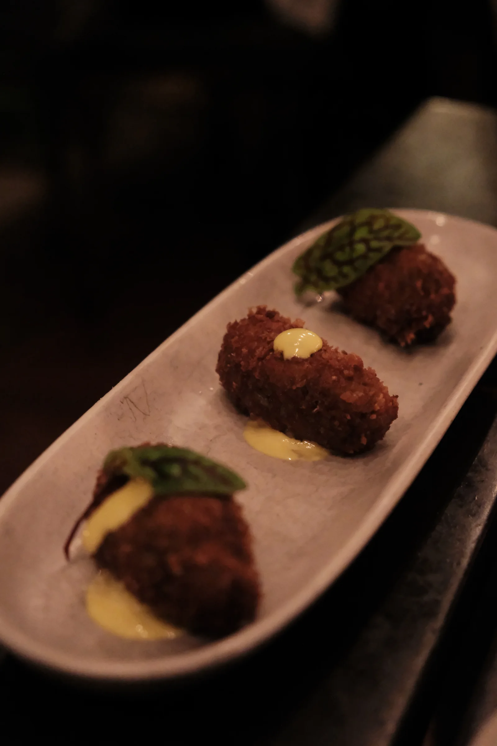 Three mushroom croquetas served with sauce and greens
