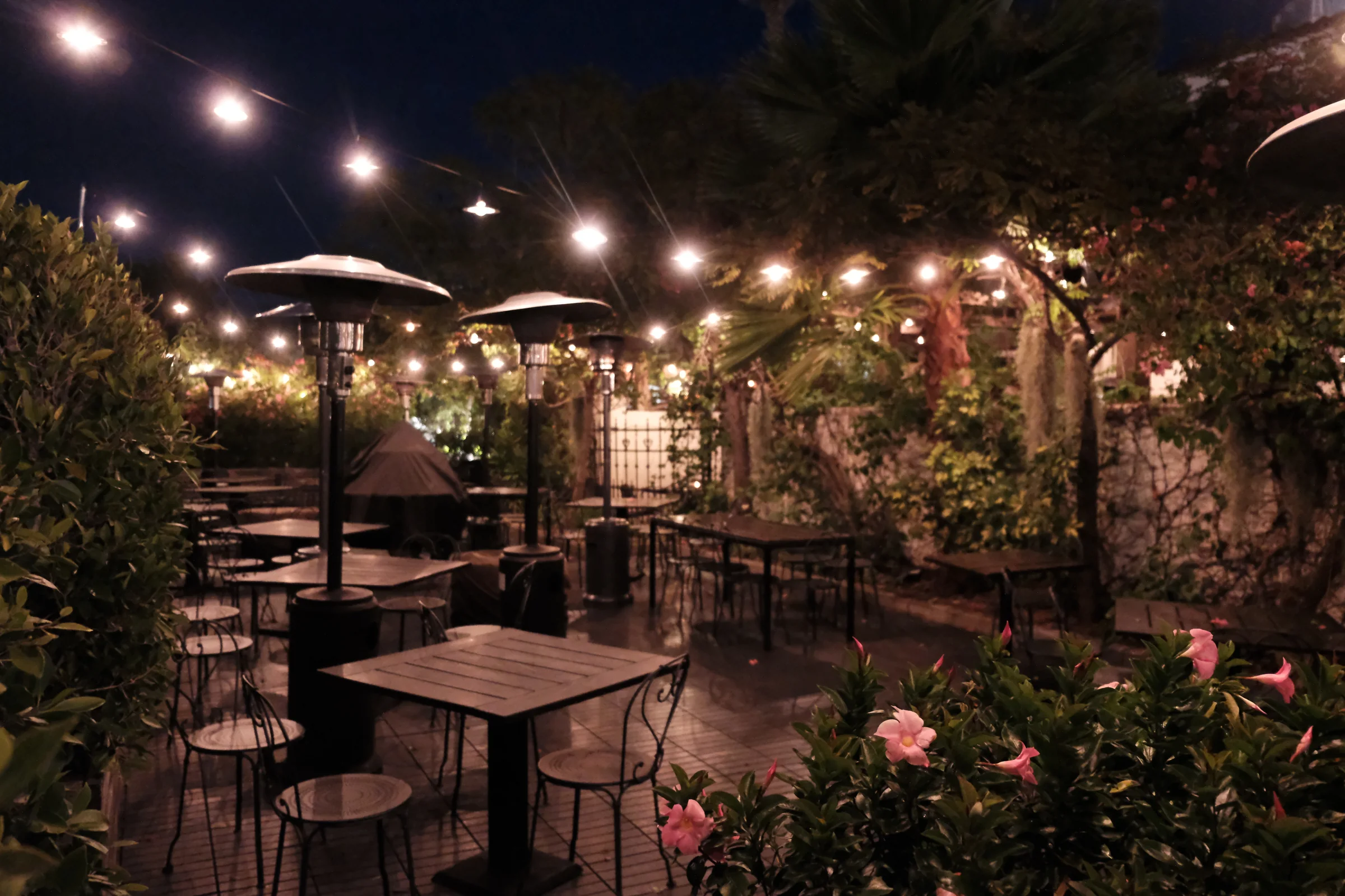 Loquita's outdoor patio with string lights, flowers, and small tables at night