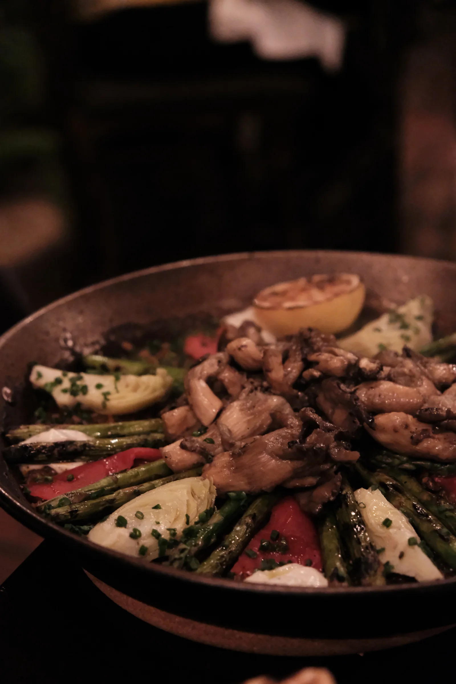 Vegetarian paella verde topped with mushrooms, asparagus, artichokes, peppers, and sauce