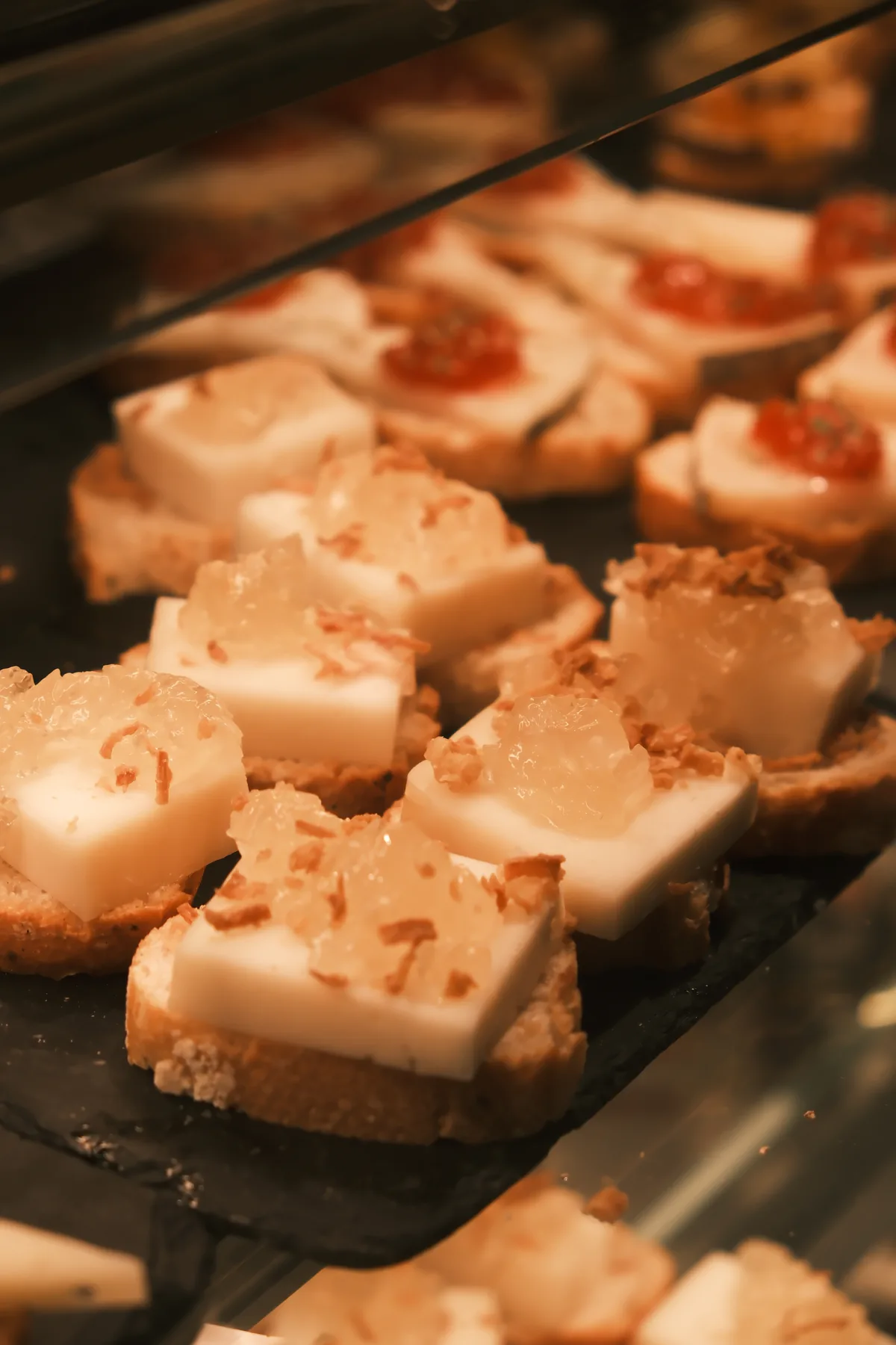 Small cheese pinchos topped with translucent preserves and crisp garnish