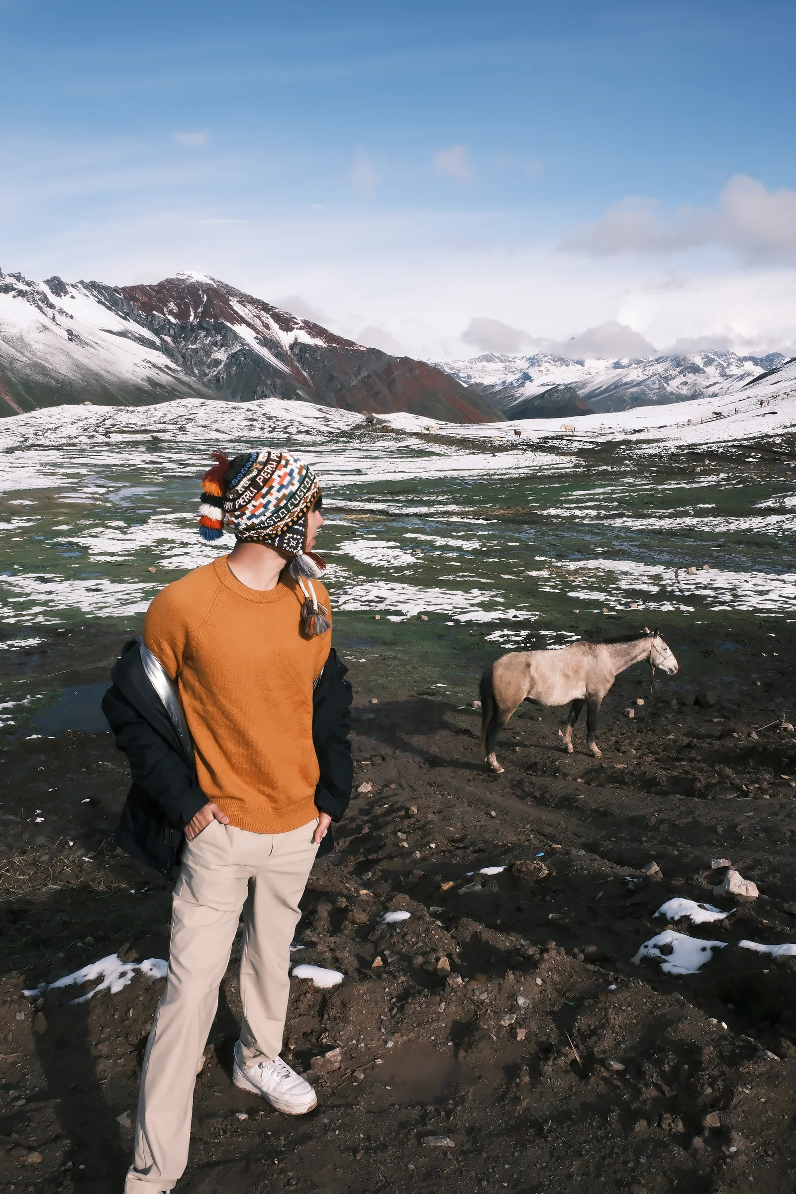 Shawn standing beside a horse in a snow-dusted Andean landscape