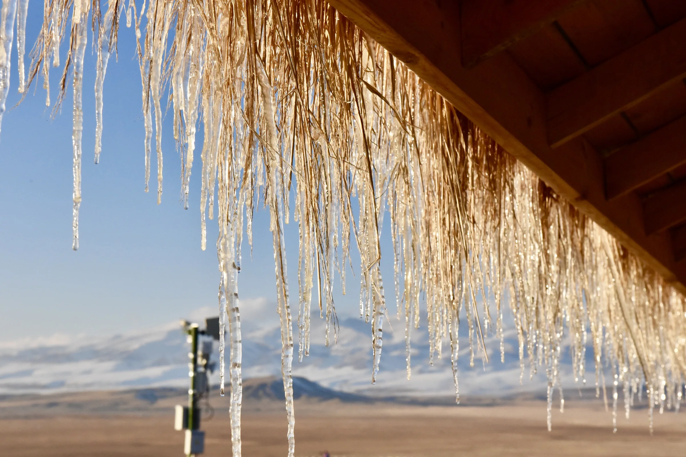 Long icicles hanging from a roof above an open plain