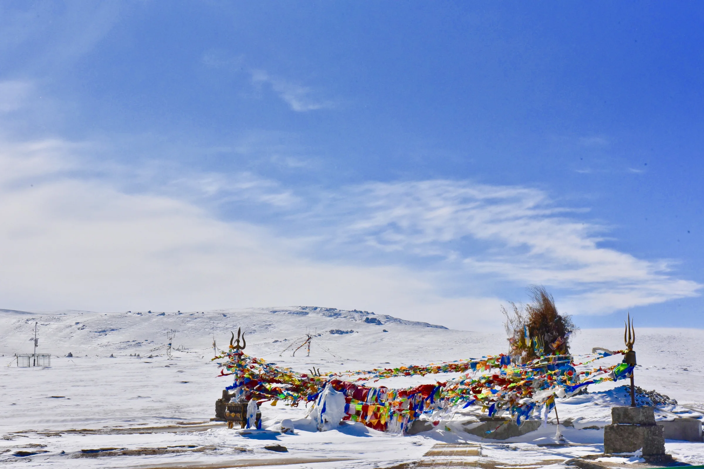 Colorful prayer flags gathered on a wide snow-covered plain